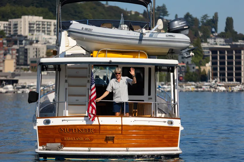 Slide: The Image of 2006 Grand Banks 47 Europa yacht on water, person waving, cityscape background. - 6