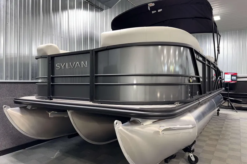 Slide: The Image of 2026 Sylvan MIRAGE X3 DLZ BAR pontoon boat in showroom, sleek design, metallic finish. - 21