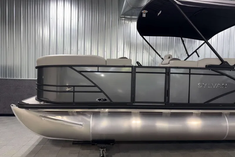 Slide: The Image of 2026 Sylvan MIRAGE X3 DLZ BAR pontoon boat in showroom, sleek design, metallic finish. - 22