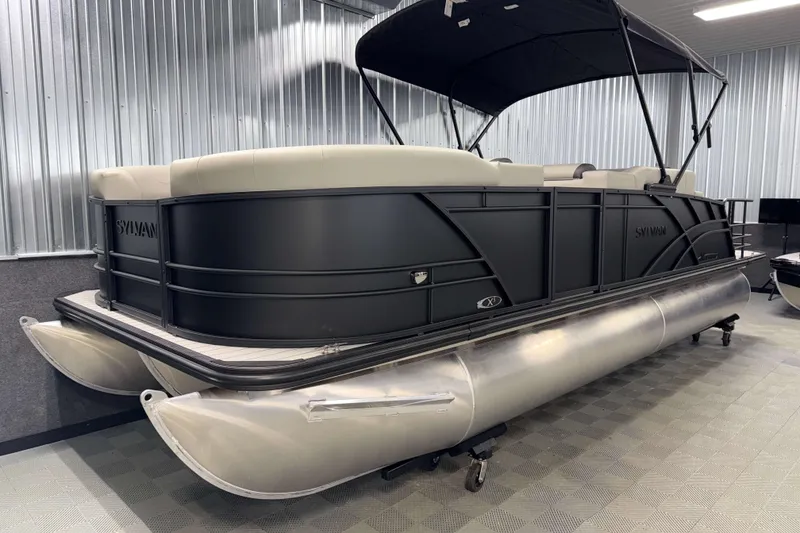 Slide: The Image of 2026 Sylvan MIRAGE X3 DLZ BAR pontoon boat in showroom, featuring sleek black design. - 21