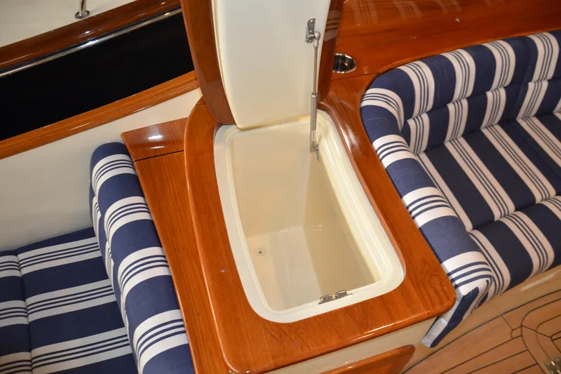 Slide: The Image of 2017 Hinckley Picnic Boat 37 MKIII interior with striped seating and wooden storage compartment. - 19