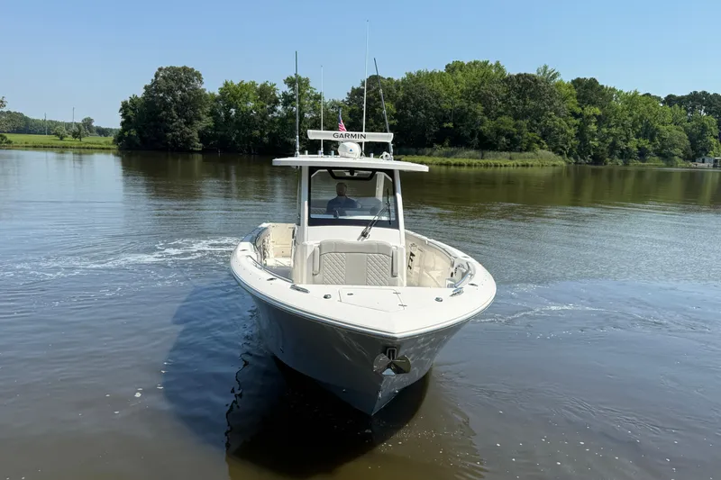 Slide: The Image of 2024 Pursuit S 328 Sport boat cruising on a calm river with lush green trees. - 10