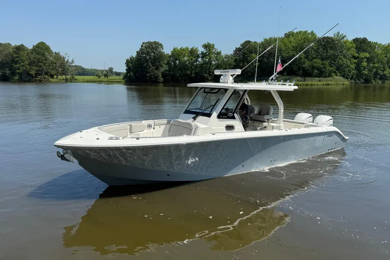 Slide: The Image of 2024 Pursuit S 328 Sport boat on calm lake with lush green trees. - 12