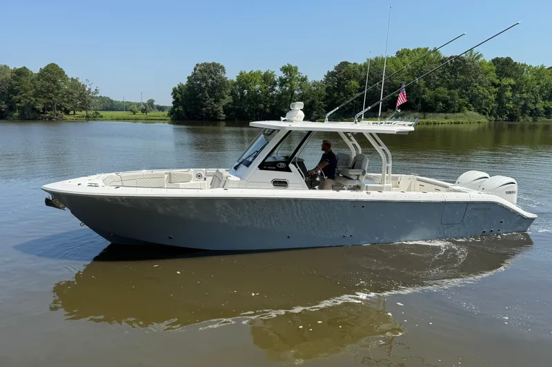 Slide: The Image of 2024 Pursuit S 328 Sport boat cruising on a calm river with lush green trees. - 13