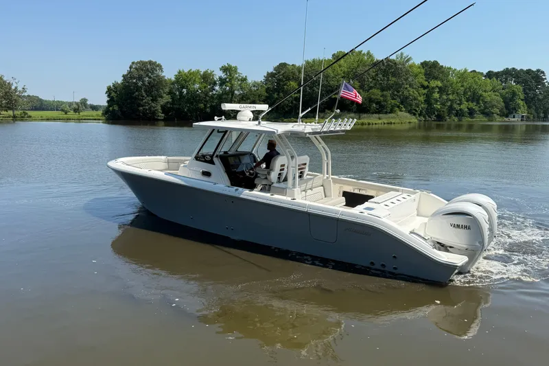 Slide: The Image of 2024 Pursuit S 328 Sport boat on a calm lake with trees in the background. - 15