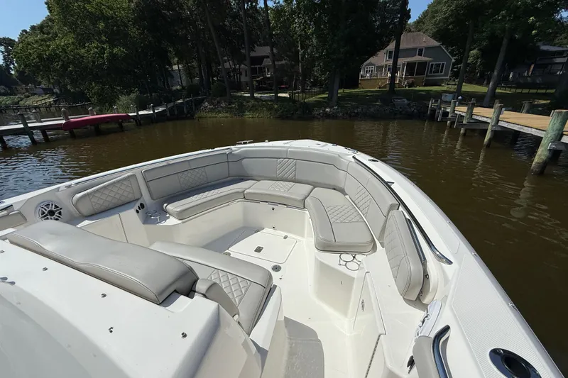 Slide: The Image of 2024 Pursuit S 328 Sport boat with spacious seating, docked by a serene waterfront. - 16