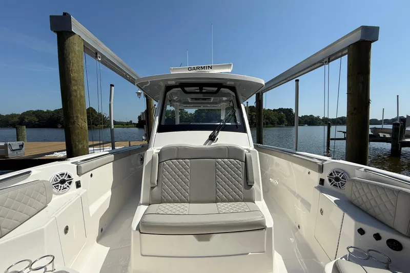Slide: The Image of 2024 Pursuit S 328 Sport boat interior with seating, docked by a serene lake. - 23