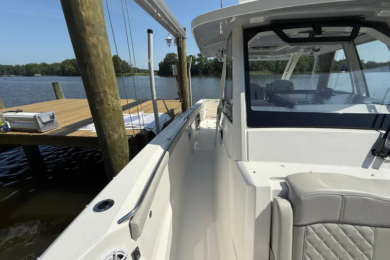 Slide: The Image of 2024 Pursuit S 328 Sport boat docked by a wooden pier on a sunny day. - 27