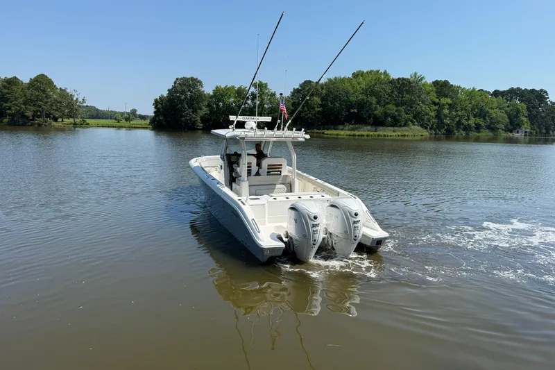 Slide: The Image of 2024 Pursuit S 328 Sport boat cruising on a calm lake with lush green surroundings. - 3