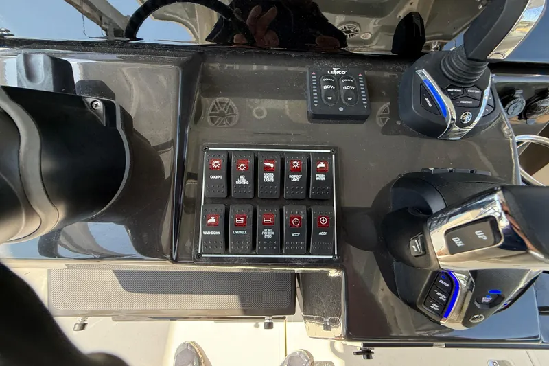 Slide: The Image of 2024 Pursuit S 328 Sport boat control panel with switches and throttle levers. - 38