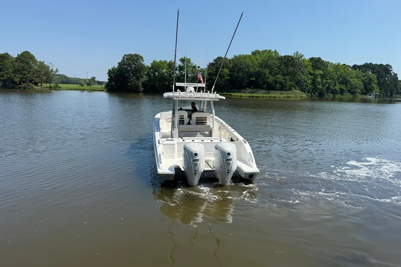 Slide: The Image of 2024 Pursuit S 328 Sport boat cruising on a calm lake with trees in the background. - 4