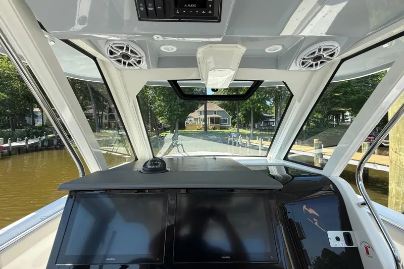 Slide: The Image of 2024 Pursuit S 328 Sport boat cockpit with advanced navigation screens and scenic waterfront view. - 43