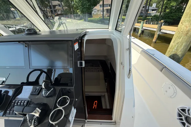 Slide: The Image of 2024 Pursuit S 328 Sport boat cockpit with helm and cabin entrance. - 45