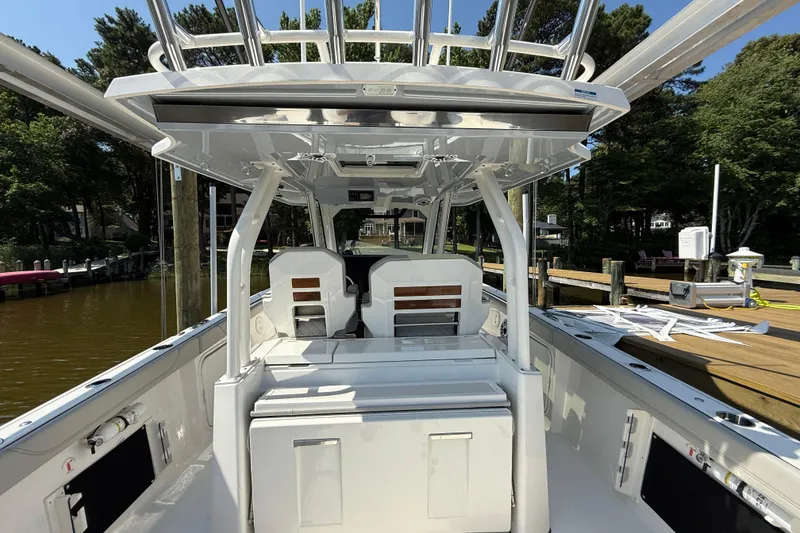 Slide: The Image of 2024 Pursuit S 328 Sport boat interior with seating and helm, docked by a wooded shoreline. - 52