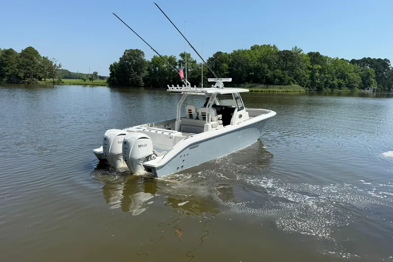 Slide: The Image of 2024 Pursuit S 328 Sport boat cruising on a calm lake with lush green surroundings. - 6