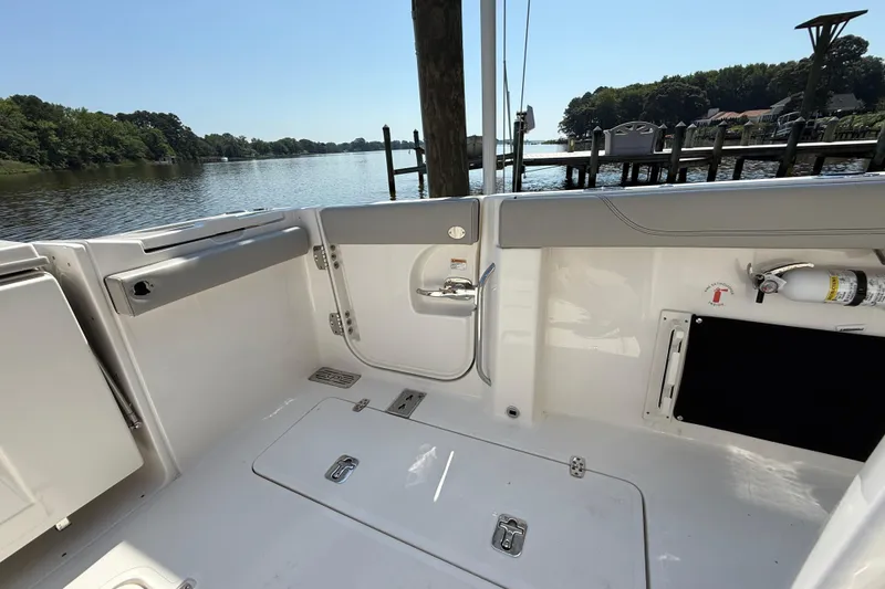 Slide: The Image of 2024 Pursuit S 328 Sport boat interior, docked by a serene lake with lush greenery. - 61