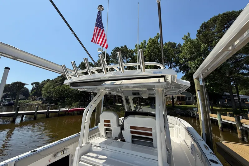 Slide: The Image of 2024 Pursuit S 328 Sport boat docked, featuring sleek design and American flag. - 64