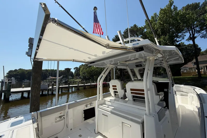 Slide: The Image of 2024 Pursuit S 328 Sport boat with canopy, docked by a serene waterfront. - 65