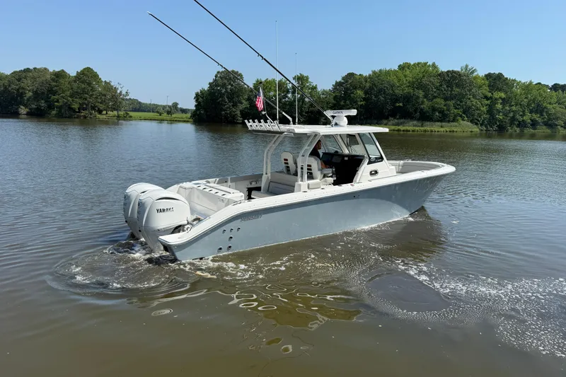 Slide: The Image of 2024 Pursuit S 328 Sport boat cruising on a calm lake with lush green surroundings. - 7