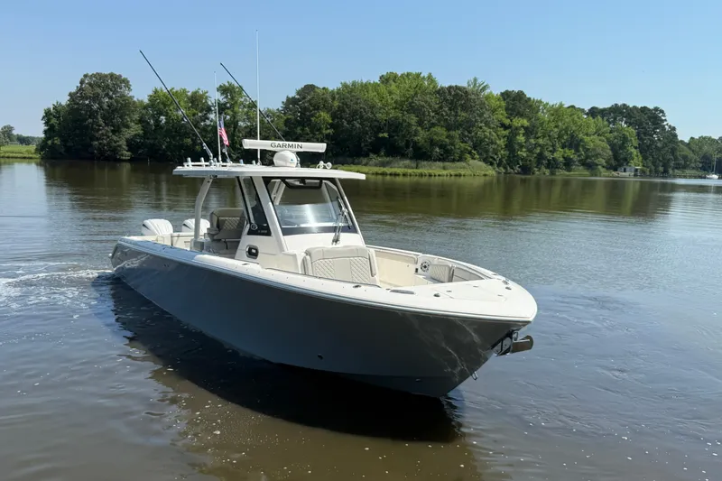 Slide: The Image of 2024 Pursuit S 328 Sport boat cruising on a calm river with lush green trees. - 9