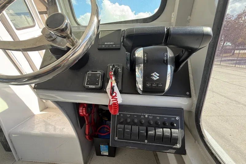 Slide: The Image of 1996 Geo Marine 24ft Work Boat dashboard with steering wheel and Suzuki controls. - 17