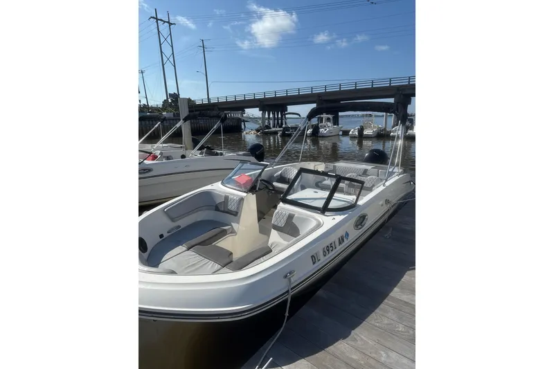 Slide: The Image of 2022 Bayliner VR6 Bowrider OB docked near a bridge on a sunny day. - 2
