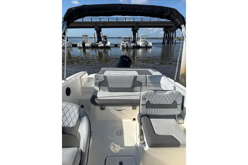Slide: The Image of 2022 Bayliner VR6 Bowrider OB interior with gray seating, docked near a bridge. - 7