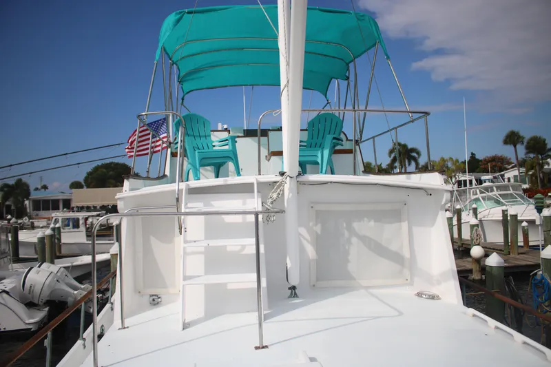 Slide: The Image of 1974 Grand Banks 42 Classic yacht with turquoise canopy and chairs, docked at marina. - 23