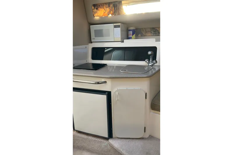 Slide: The Image of 1999 Chaparral Signature 29 boat kitchenette with microwave, sink, and storage cabinets. - 19