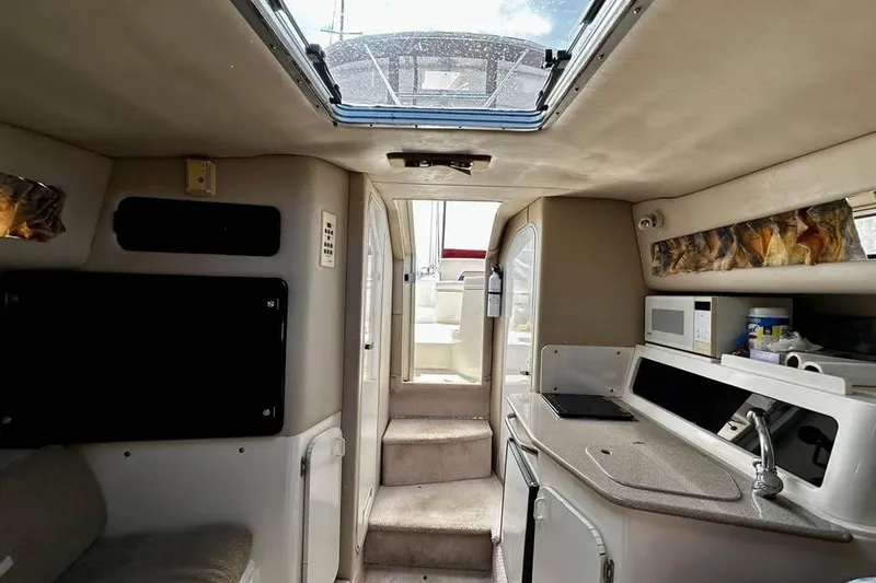 Slide: The Image of Interior of a 1999 Chaparral Signature 29 boat, featuring a compact kitchen and seating area. - 31