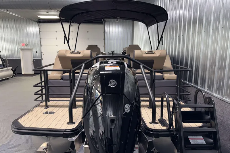 Slide: The Image of 2026 Sylvan L3 LZ pontoon boat with black motor in a metal-walled showroom. - 28