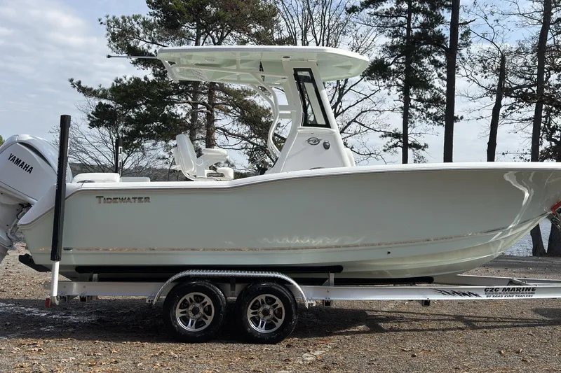 Slide: The Image of 2026 Tidewater 232 LXF boat on trailer, parked near trees and water. - 3