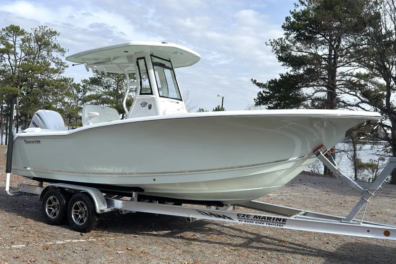 Slide: The Image of 2026 Tidewater 232 LXF boat on trailer, parked outdoors near trees and water. - 4