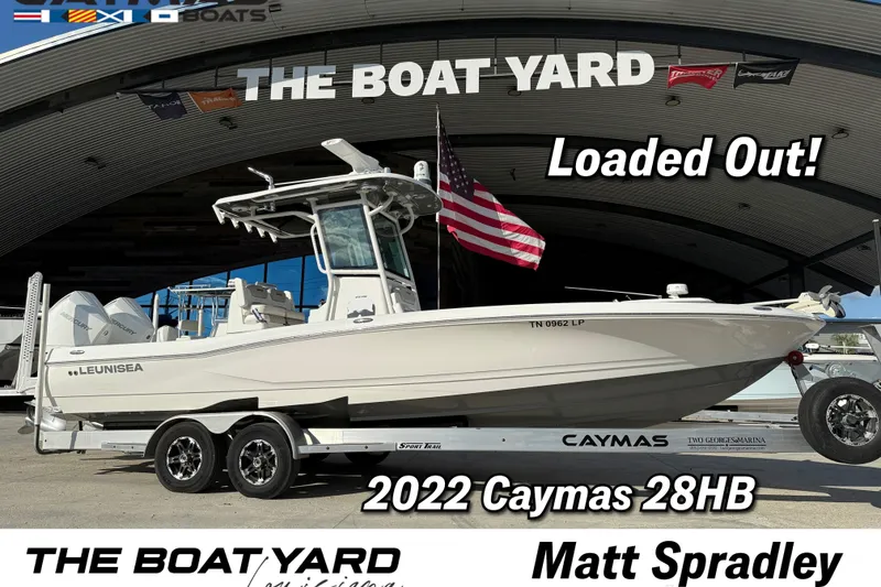 Slide: The Image of 2022 Caymas 28 HB Twin boat on trailer, displayed outdoors with American flag. - 1