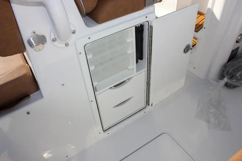 Slide: The Image of 2026 Sea Hunt Ultra 285 SE boat interior storage compartment with open door and drawers. - 18