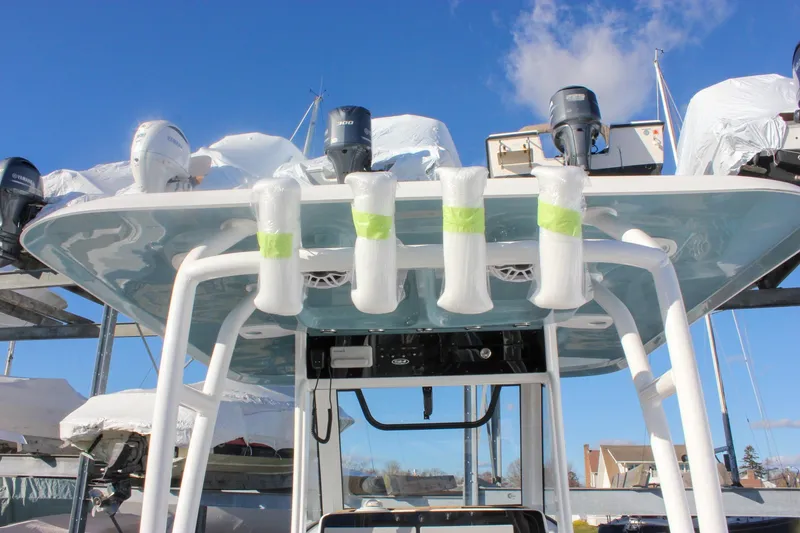 Slide: The Image of 2026 Sea Hunt Ultra 285 SE boat with multiple engines and rod holders, docked under clear sky. - 70