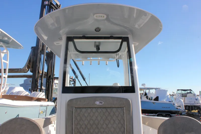 Slide: The Image of 2026 Sea Hunt Ultra 265 SE boat with T-top and console, docked under clear blue sky. - 36