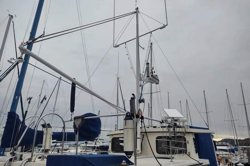 Slide: The Image of 1990 Nordic Tug 32 in marina, surrounded by sailboats under cloudy sky. - 10