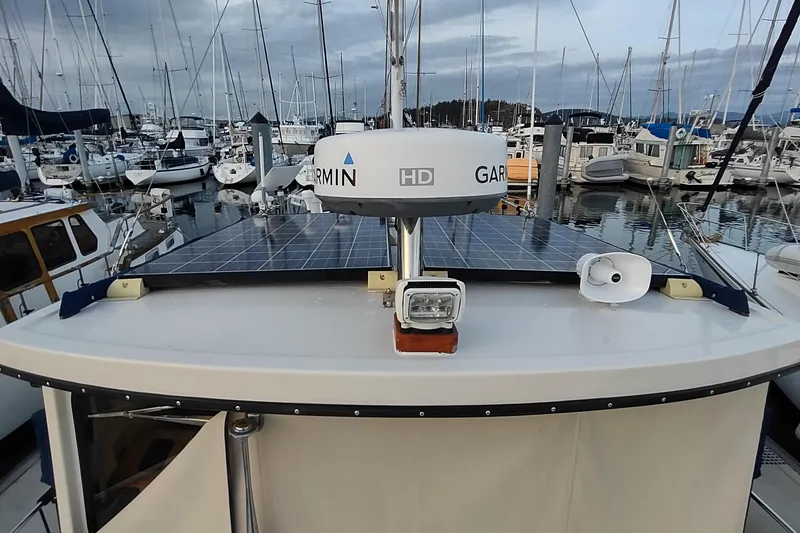 Slide: The Image of 1990 Nordic Tug 32 with solar panels and radar, docked in a marina. - 14