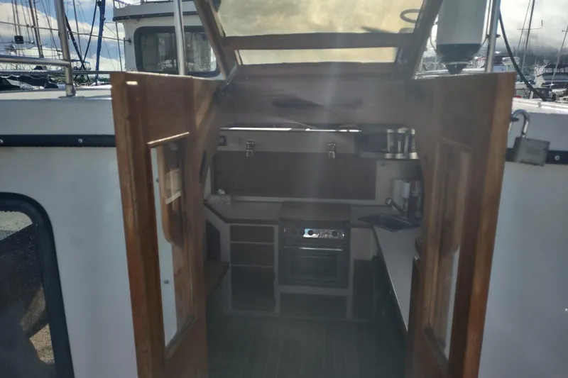 Slide: The Image of Interior view of a 1990 Nordic Tug 32, showcasing the compact kitchen area. - 17