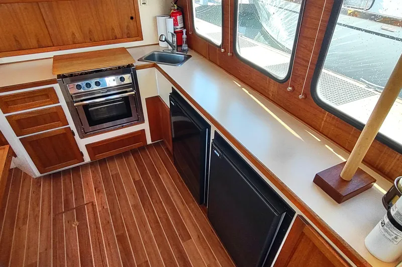 Slide: The Image of 1990 Nordic Tug 32 interior kitchen with wood cabinetry, stove, sink, and windows. - 21
