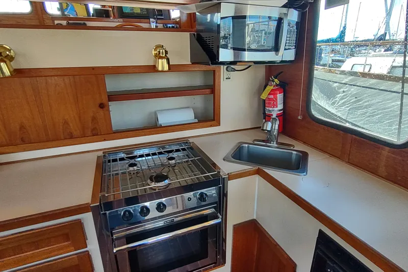 Slide: The Image of 1990 Nordic Tug 32 galley with stove, microwave, sink, and fire extinguisher. - 23