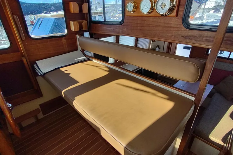 Slide: The Image of 1990 Nordic Tug 32 interior with cushioned seating and wooden flooring. - 33