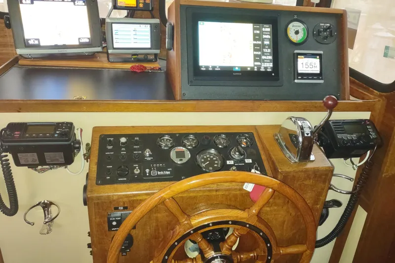 Slide: The Image of 1990 Nordic Tug 32 helm with wooden wheel, gauges, and control panel. - 37