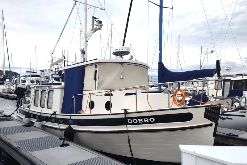 Slide: The Image of 1990 Nordic Tug 32 docked at marina, featuring blue and white design. - 4