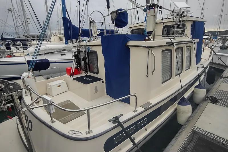 Slide: The Image of 1990 Nordic Tug 32 docked at marina, featuring blue covers and fenders. - 7