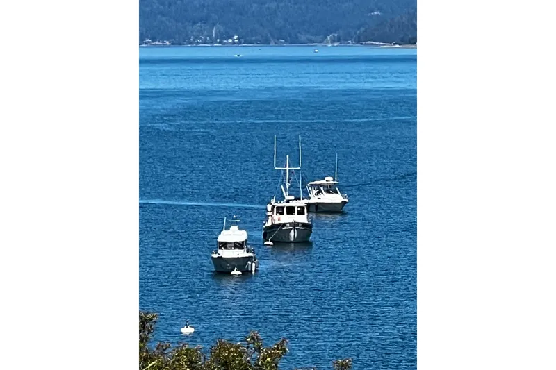 Slide: The Image of Boats on a serene lake, featuring a 1990 Nordic Tug 32. - 72