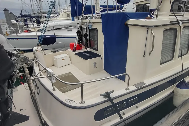 Slide: The Image of 1990 Nordic Tug 32 docked, featuring a spacious deck and nautical equipment. - 8