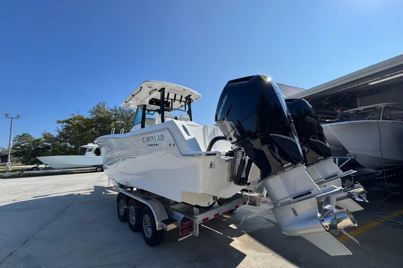 Slide: The Image of 2026 Caymas 30 CT boat with dual Mercury engines on a trailer under clear blue sky. - 14
