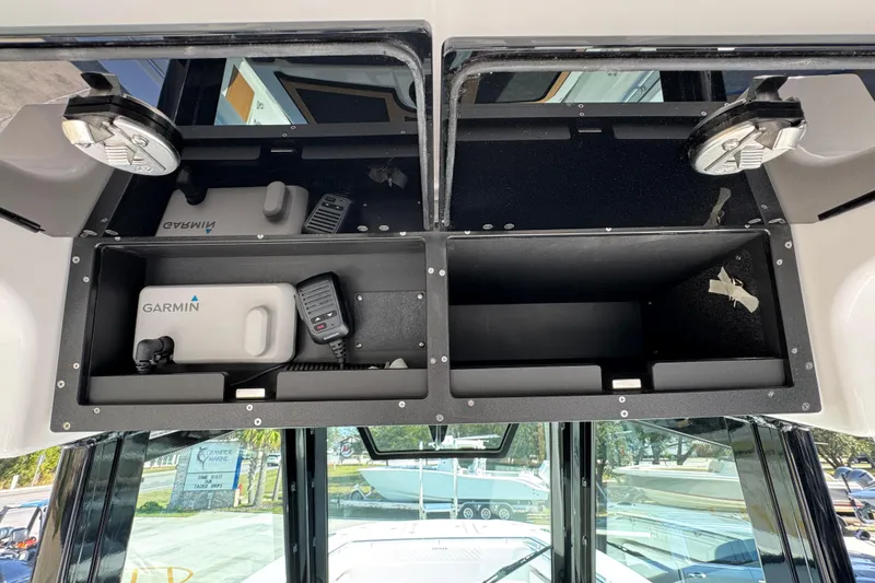Slide: The Image of Storage compartments in a 2026 Caymas 30 CT boat, featuring Garmin equipment and a microphone. - 33